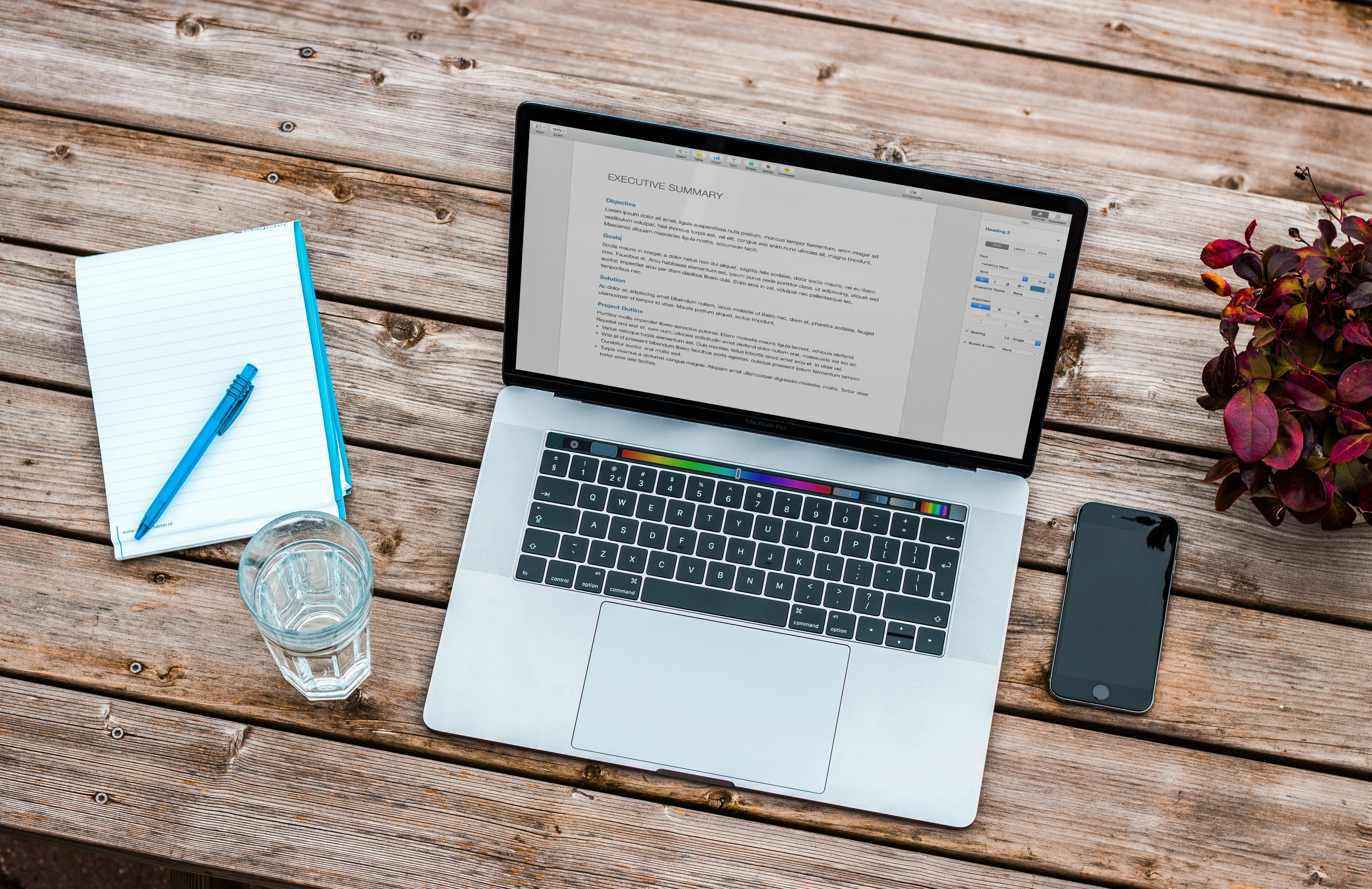 Arial view of a laptop with a blank notebook and glass of water to the left of it.